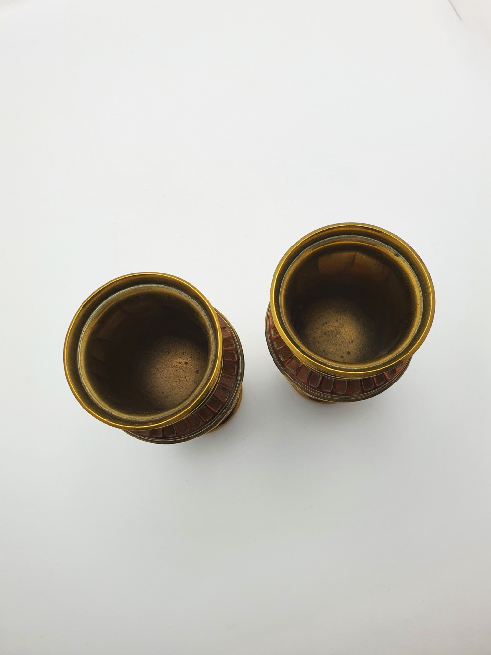 A pair of antique French copper urns featuring brass rims, pedestal bases, and chased floral motifs. View IV