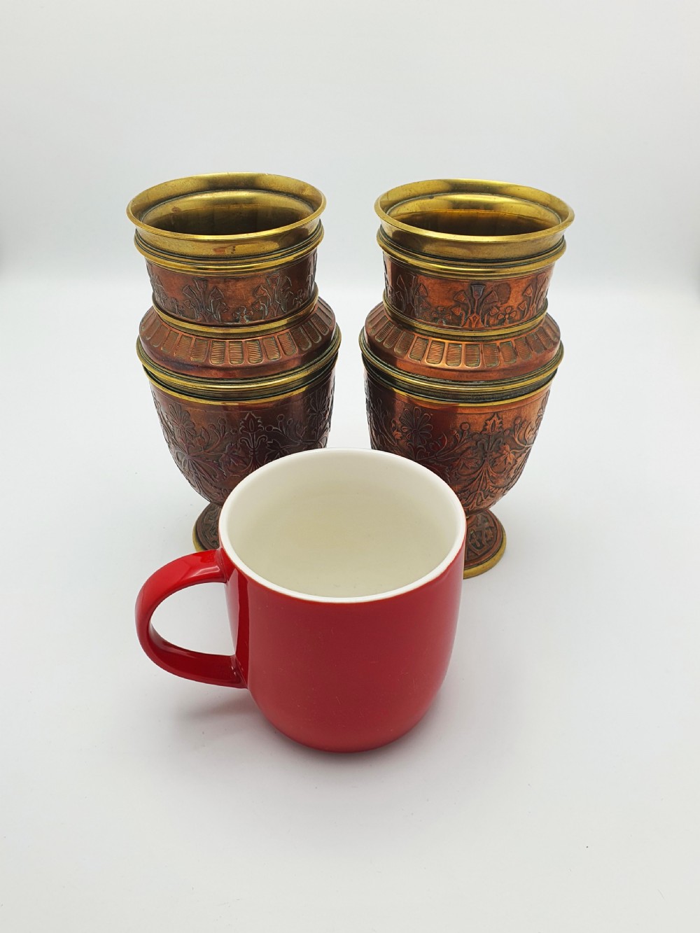 A pair of antique French copper urns featuring brass rims, pedestal bases, and chased floral motifs. View VIII