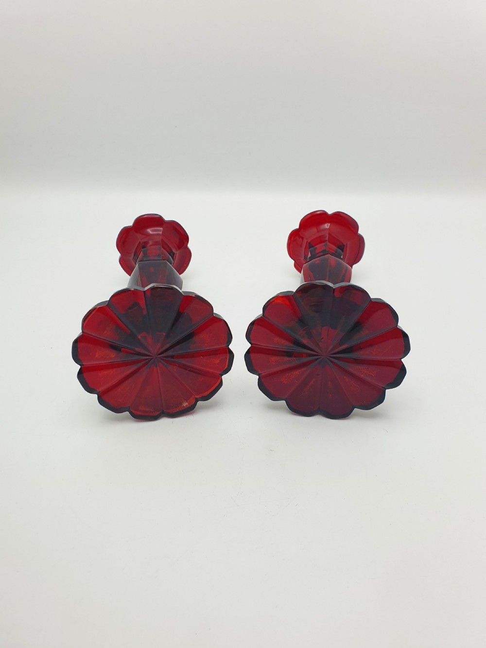 A pair of late 19th-century Continental ruby red cut glass candlesticks featuring faceted stems and scalloped bases. View III