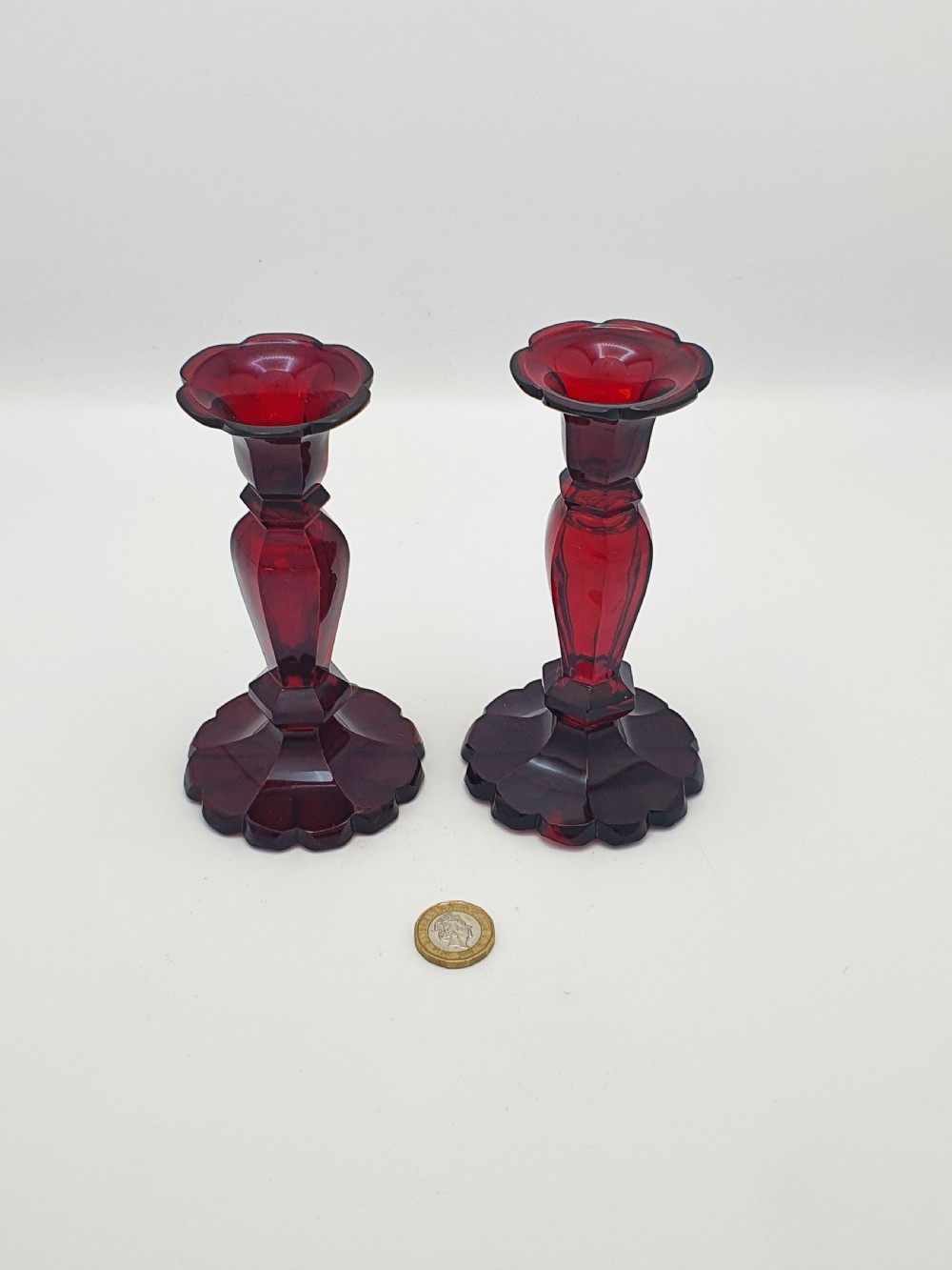 A pair of late 19th-century Continental ruby red cut glass candlesticks featuring faceted stems and scalloped bases. View IV