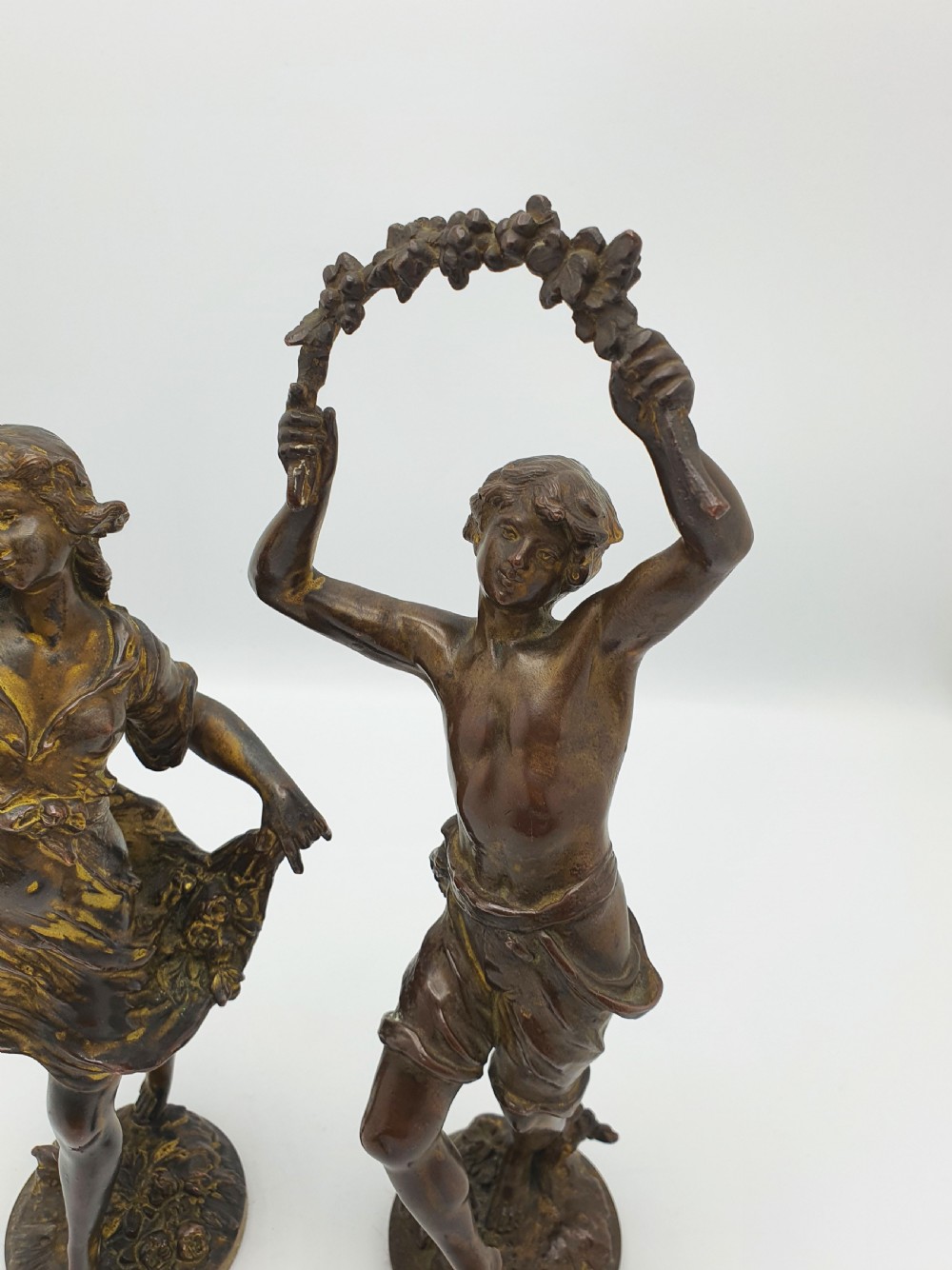 A pair of dark patinated bronze figurines depicting male and female harvest dancers holding floral garlands. View III