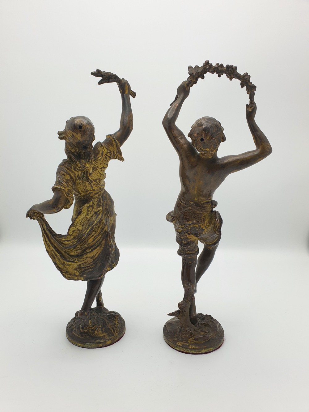 A pair of dark patinated bronze figurines depicting male and female harvest dancers holding floral garlands. View VI