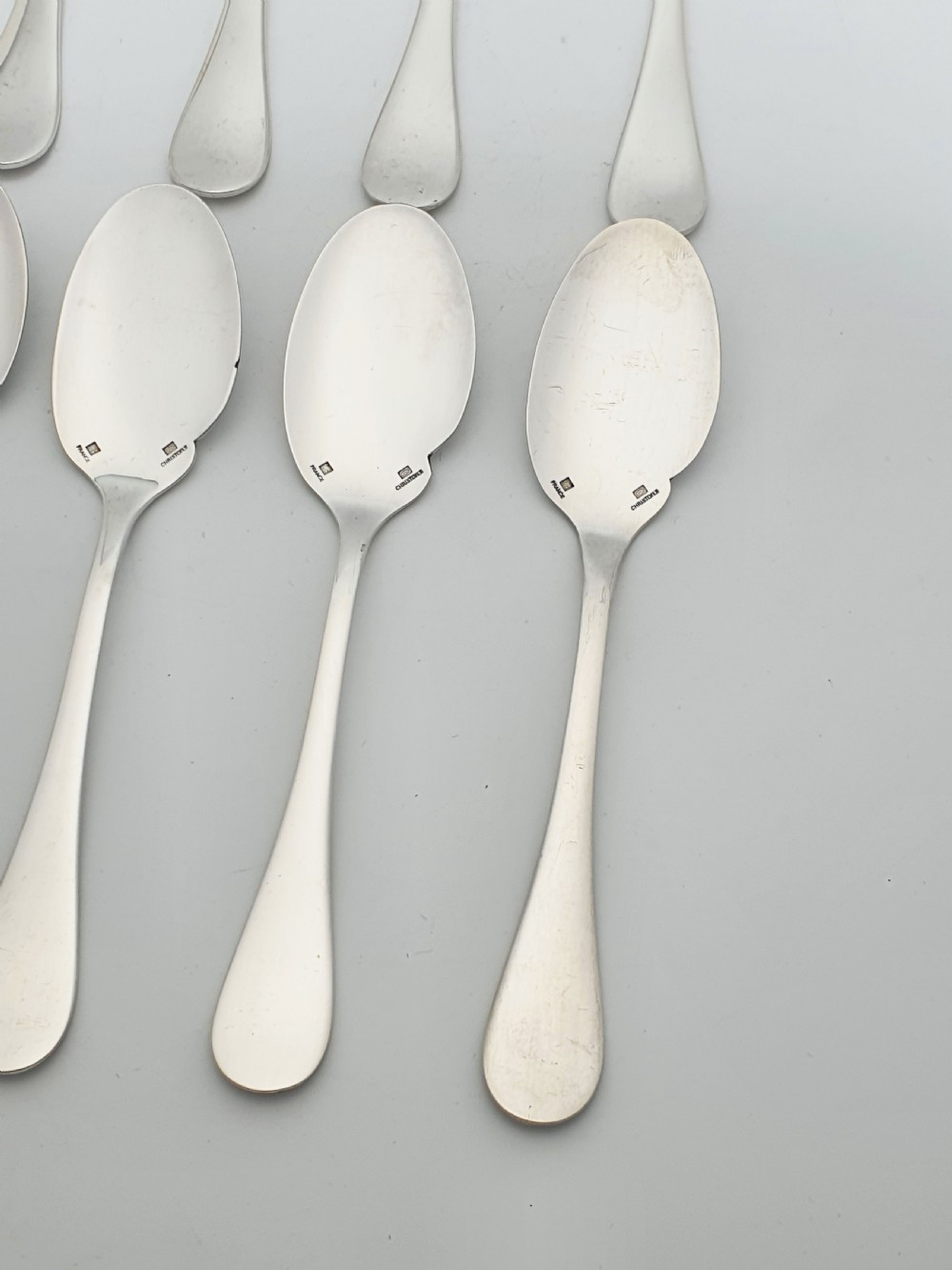 A set of eight French silver-plated dessert spoons arranged in a fan shape against a neutral background. View II