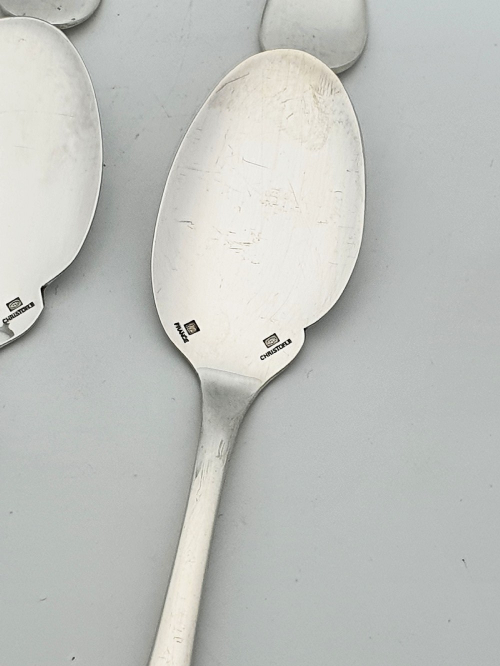 A set of eight French silver-plated dessert spoons arranged in a fan shape against a neutral background. View III