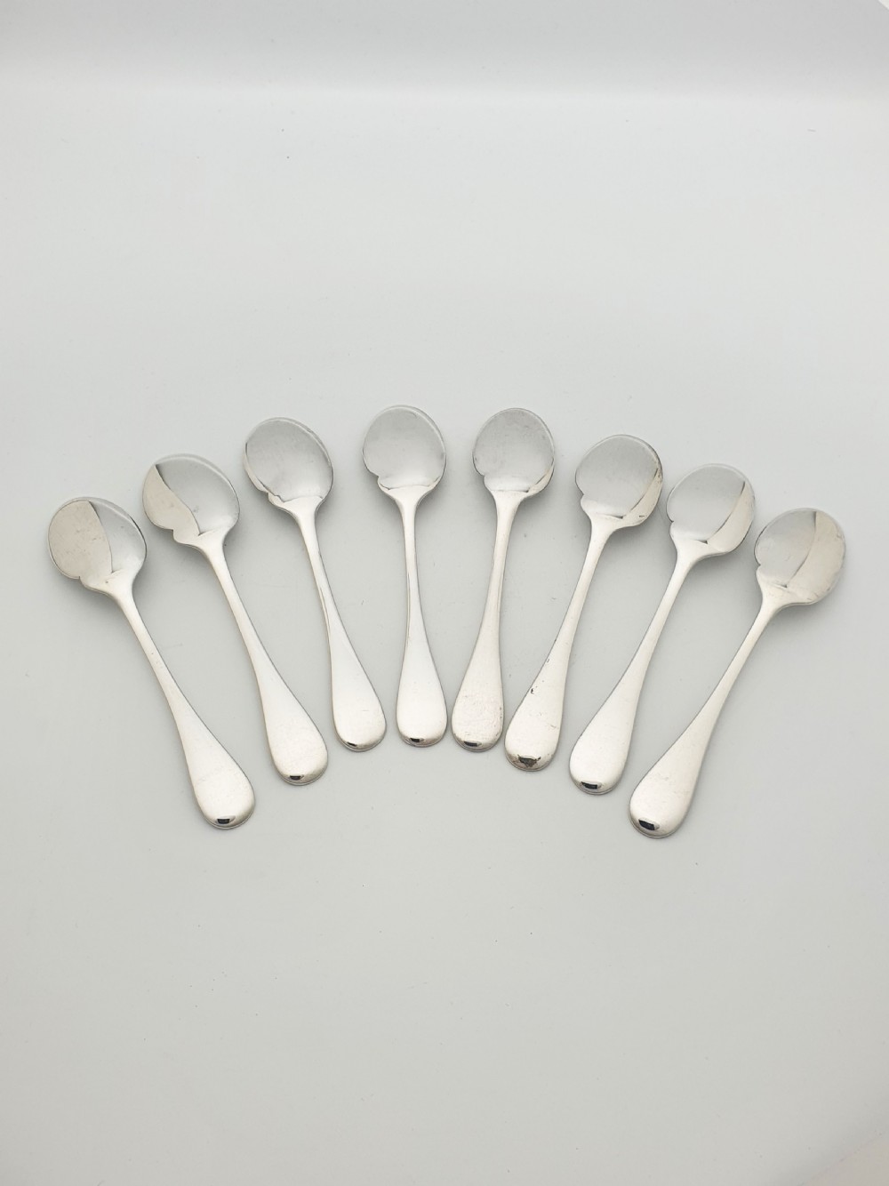 A set of eight French silver-plated dessert spoons arranged in a fan shape against a neutral background. View IV