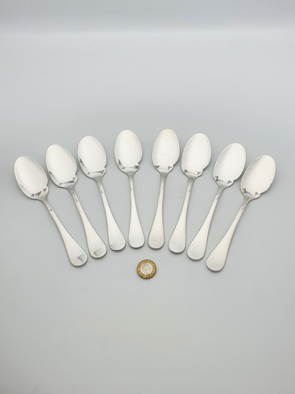 A set of eight French silver-plated dessert spoons arranged in a fan shape against a neutral background. View V