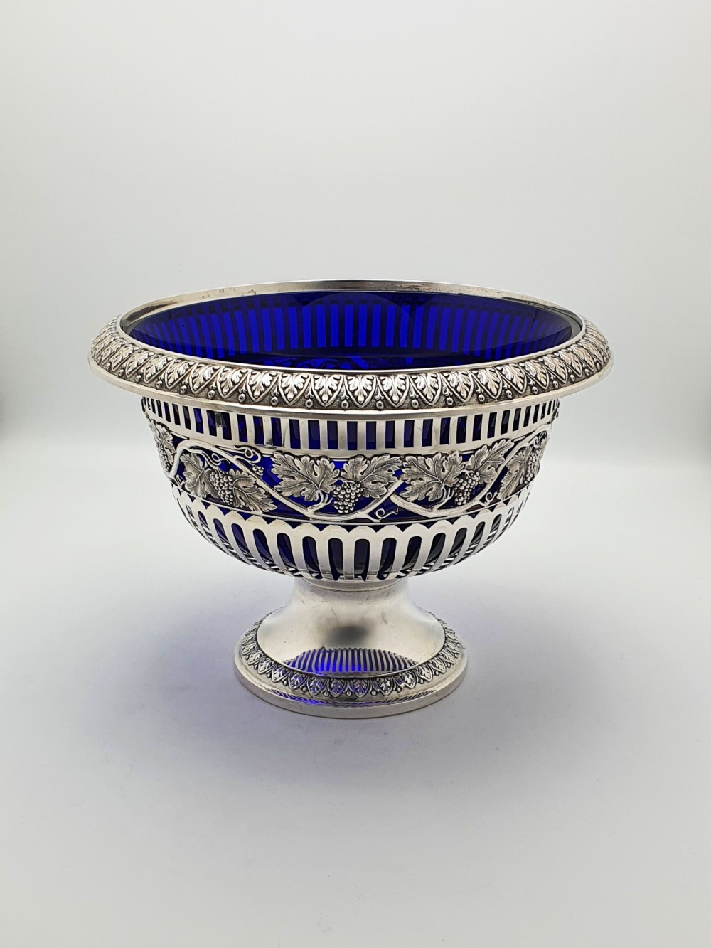 A German 800 silver centrepiece bowl featuring a pierced leaf and vine motif frame on a pedestal base with a cobalt blue glass liner.