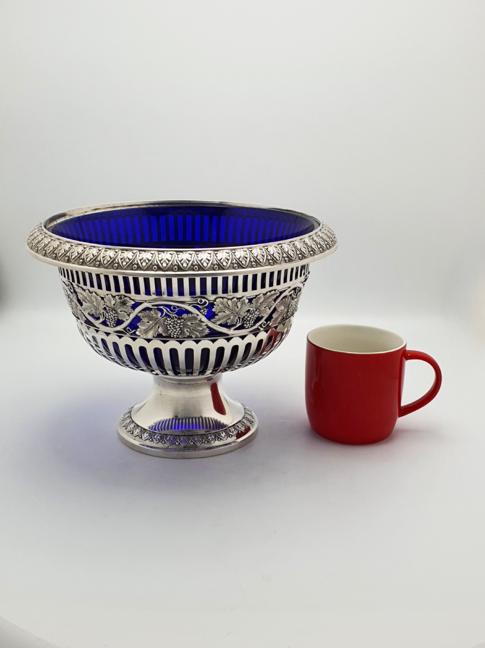 A German 800 silver centrepiece bowl featuring a pierced leaf and vine motif frame on a pedestal base with a cobalt blue glass liner. View X