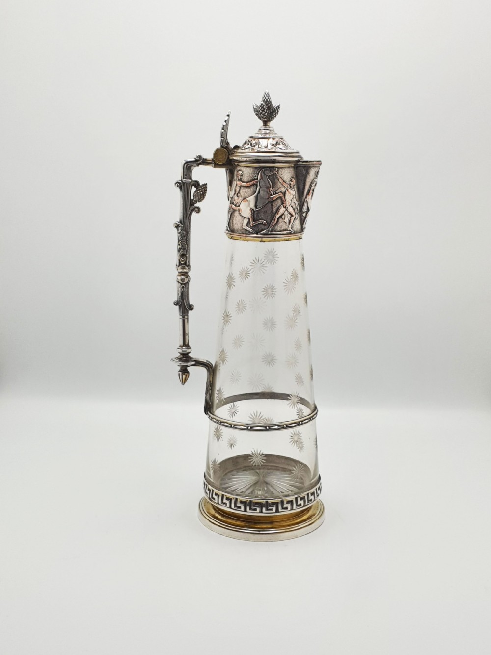 A tall Victorian silver-plated and etched glass claret jug featuring classical reliefs, a Greek key border, and star-cut engravings.
