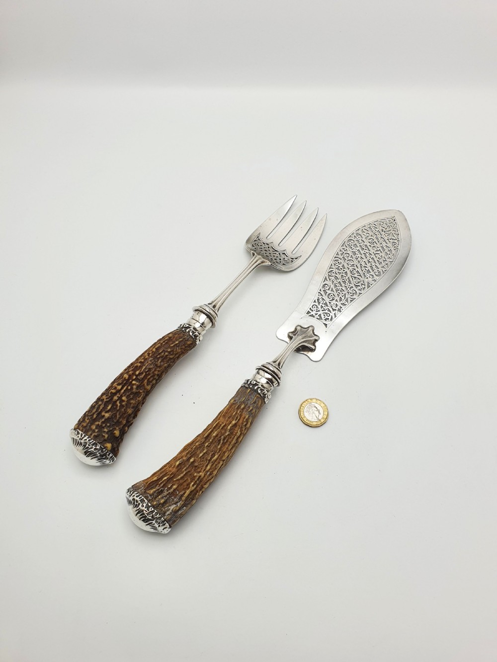 A pair of Victorian silver fish servers featuring intricately engraved pierced blades and natural stag antler handles. View IX
