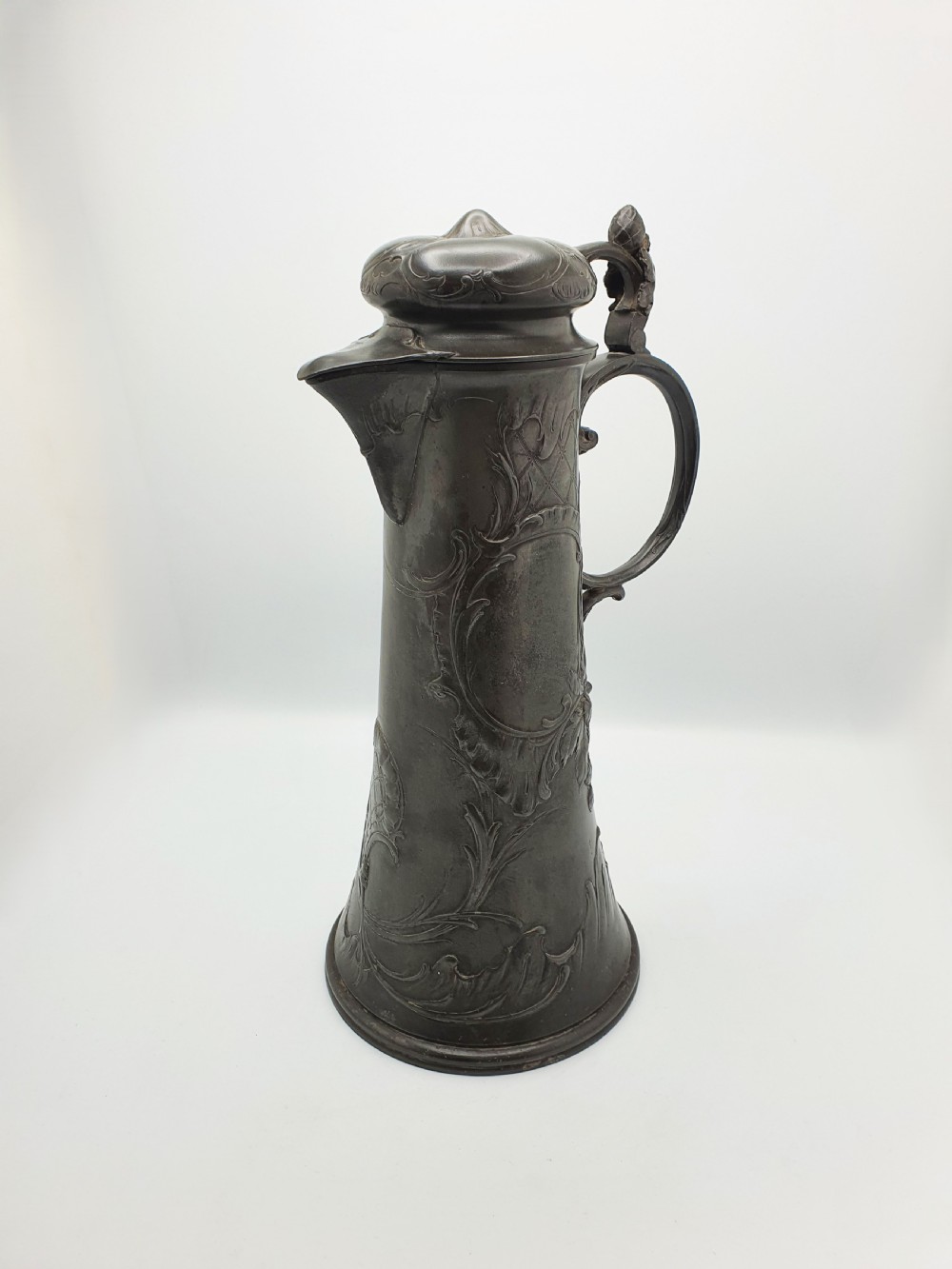 A tall German Art Nouveau pewter beer flagon featuring relief hops decoration, a flared base, a hinged lid, and a sweeping curved handle. View II