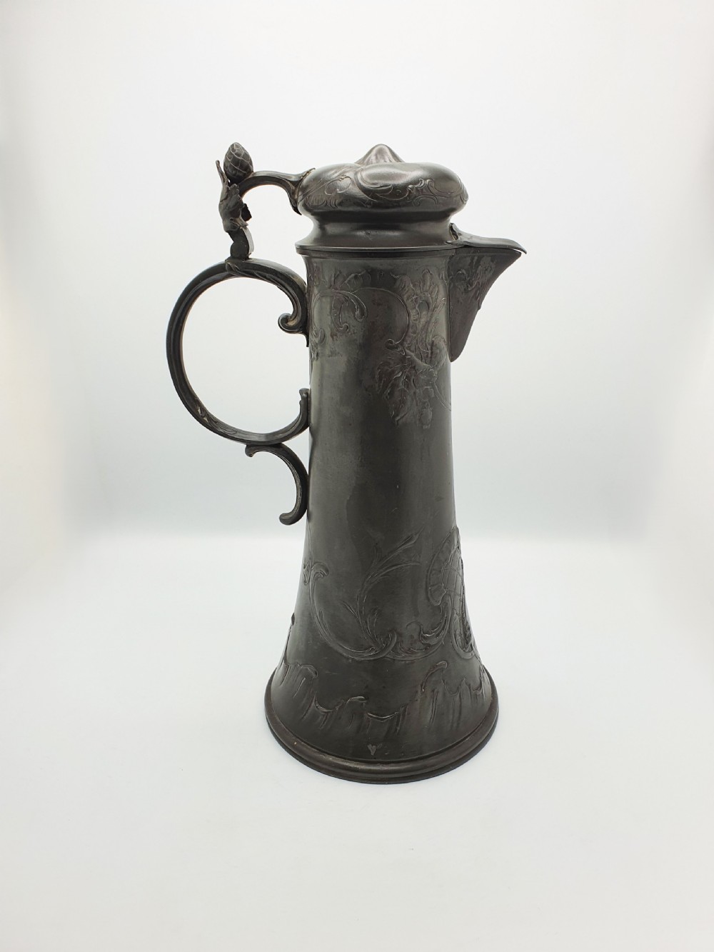 A tall German Art Nouveau pewter beer flagon featuring relief hops decoration, a flared base, a hinged lid, and a sweeping curved handle. View III