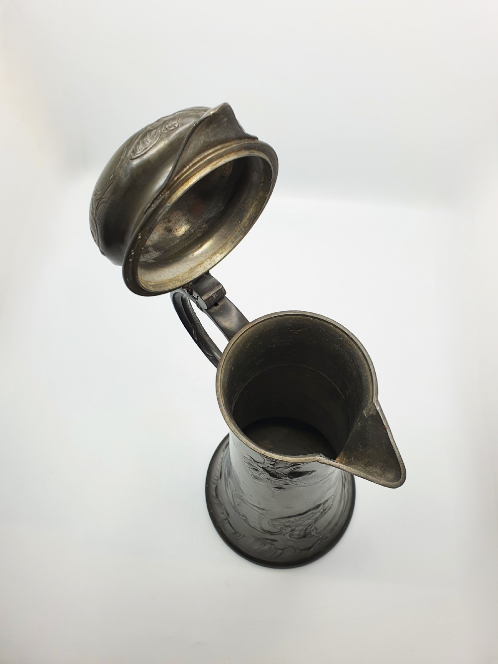 A tall German Art Nouveau pewter beer flagon featuring relief hops decoration, a flared base, a hinged lid, and a sweeping curved handle. View IV