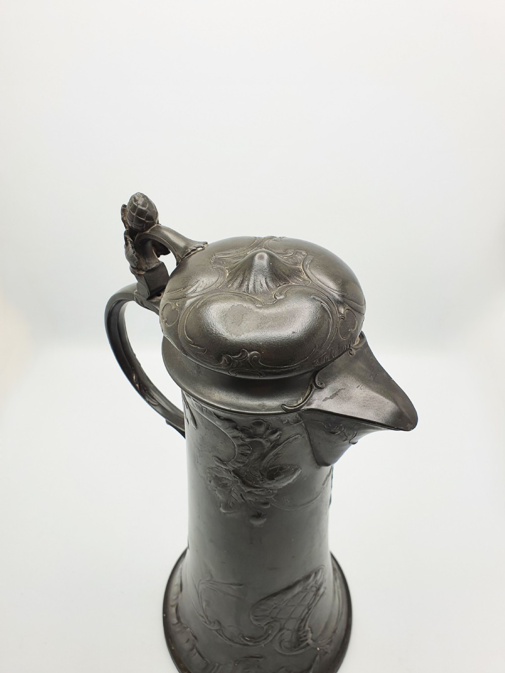 A tall German Art Nouveau pewter beer flagon featuring relief hops decoration, a flared base, a hinged lid, and a sweeping curved handle. View V