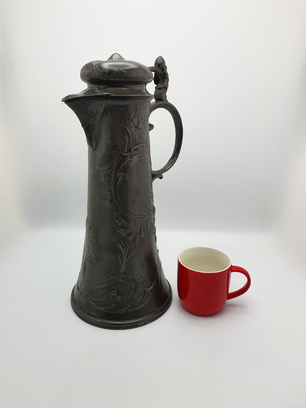 A tall German Art Nouveau pewter beer flagon featuring relief hops decoration, a flared base, a hinged lid, and a sweeping curved handle. View VII