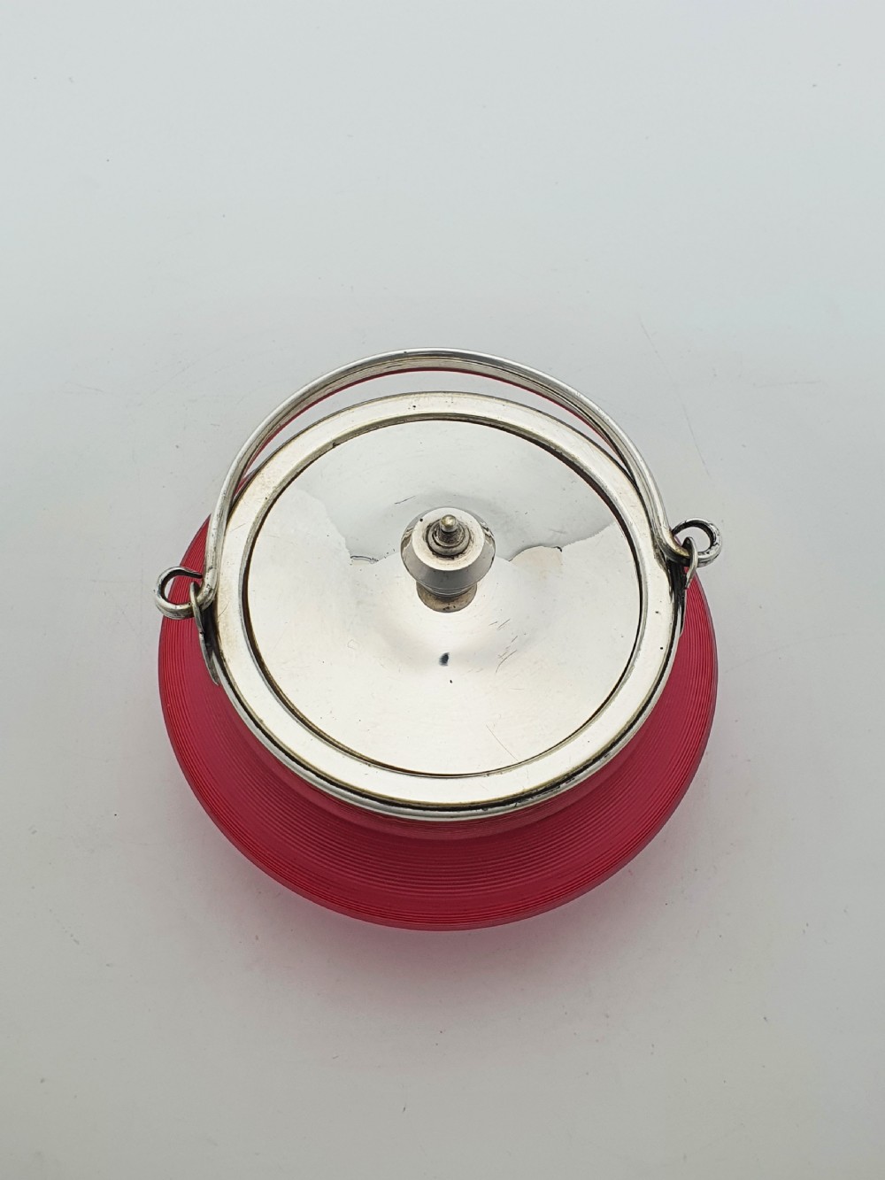 A ribbed cranberry glass biscuit barrel featuring a silver-plated fitted rim, flat lid, and hinged swing handle. View V