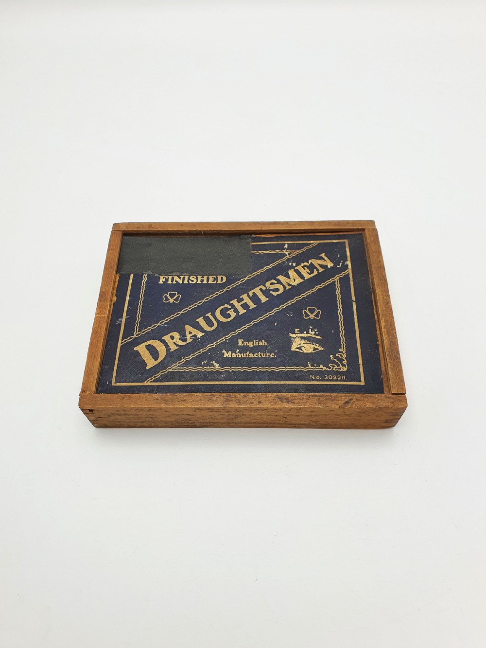 A set of turned boxwood and dark-stained wooden draughtsmen displayed in front of their original wooden slide-lid box with a printed label. View II