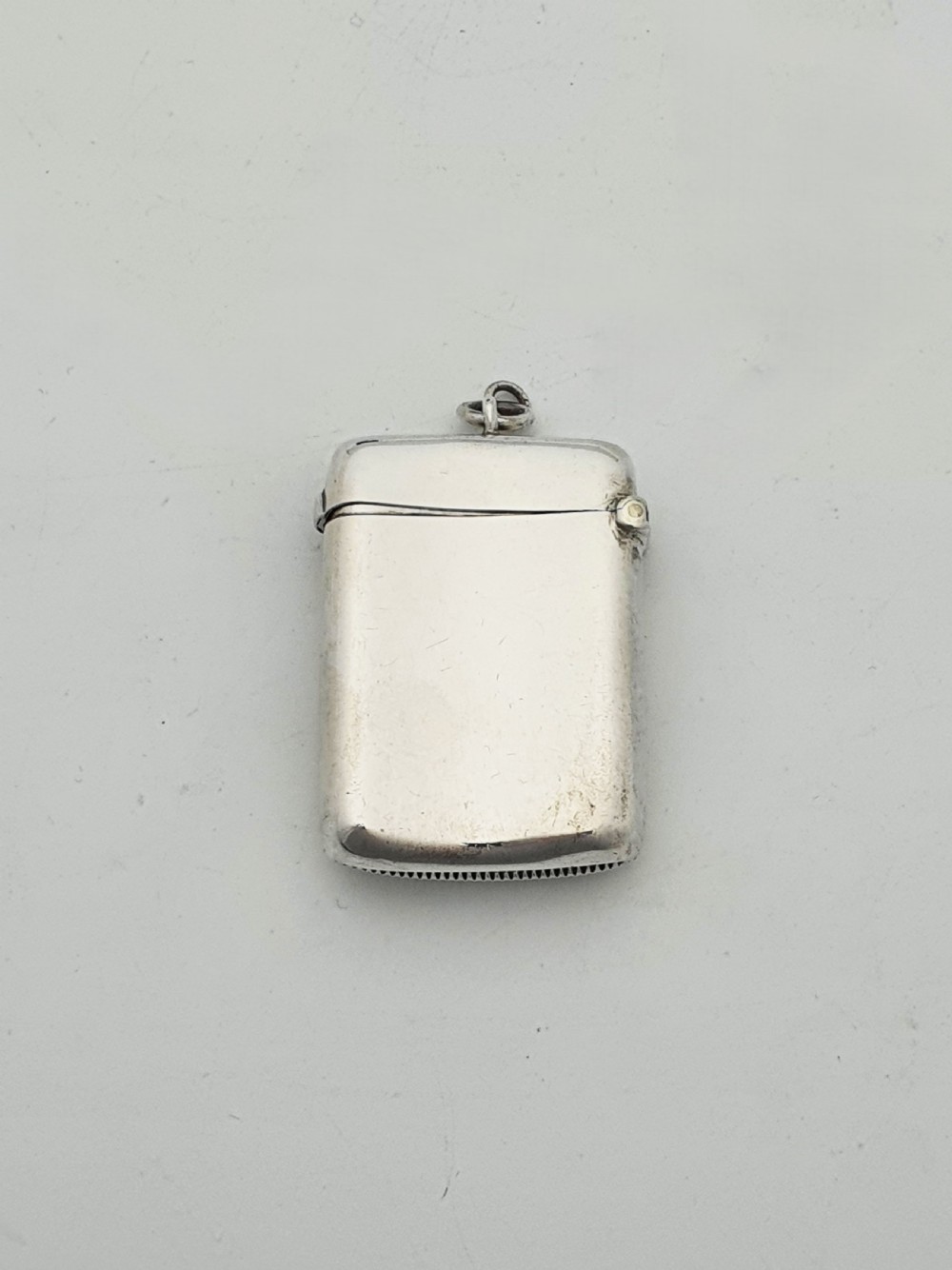 An antique sterling silver vesta case engraved with a golfer and St. Andrews lettering, displayed inside an open blue velvet box. View II