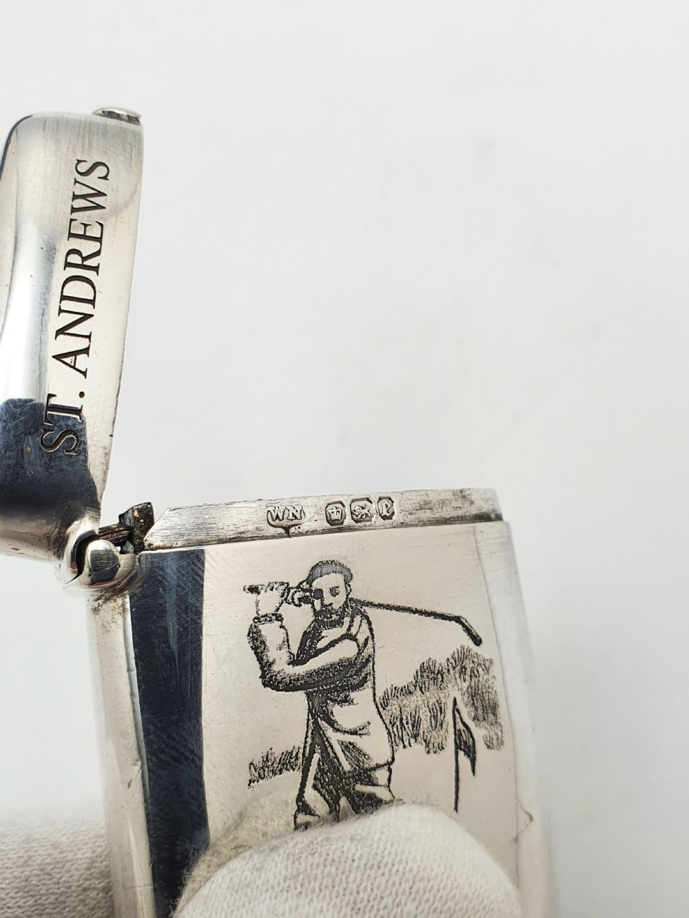 An antique sterling silver vesta case engraved with a golfer and St. Andrews lettering, displayed inside an open blue velvet box. View VI