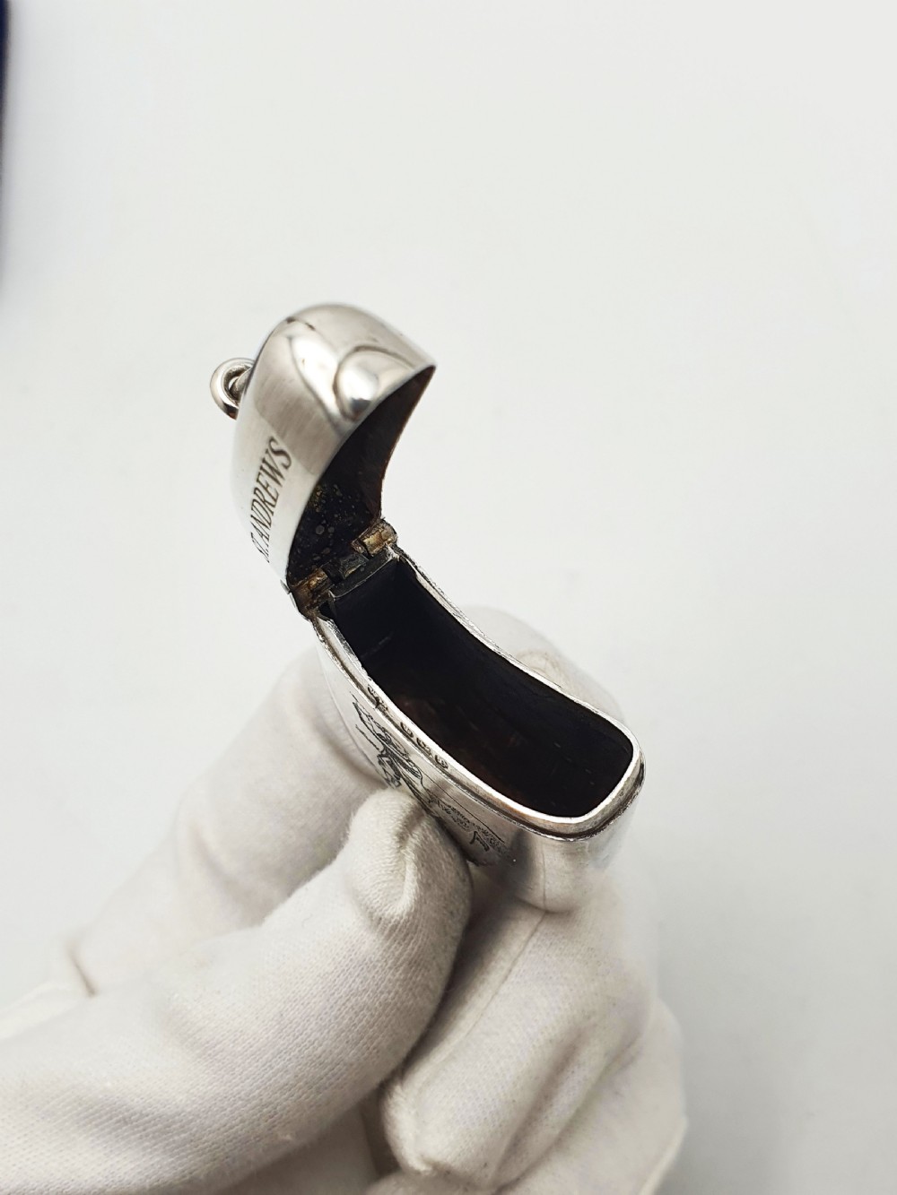 An antique sterling silver vesta case engraved with a golfer and St. Andrews lettering, displayed inside an open blue velvet box. View VII