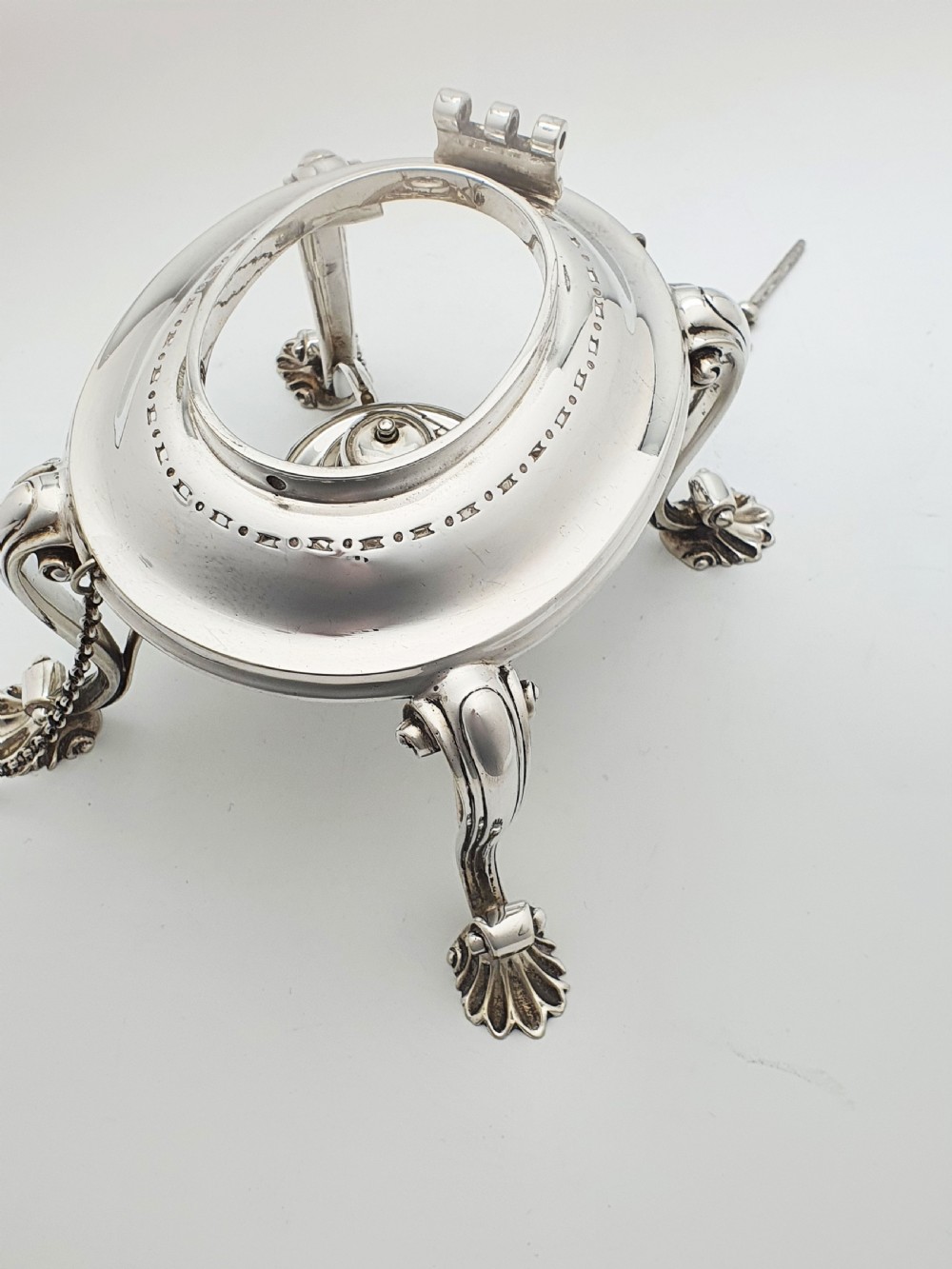 An antique Georgian-style silver-plated spirit kettle resting on a three-legged burner stand with shell feet and an ebony handle. View XII