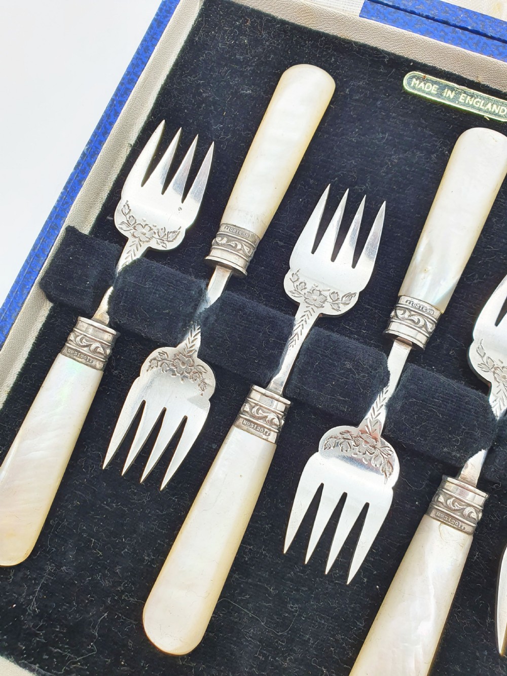 A cased set of six Victorian hors doeuvres forks featuring mother-of-pearl handles and engraved silver-plated tines, presented in a blue fabric-lined box. View II