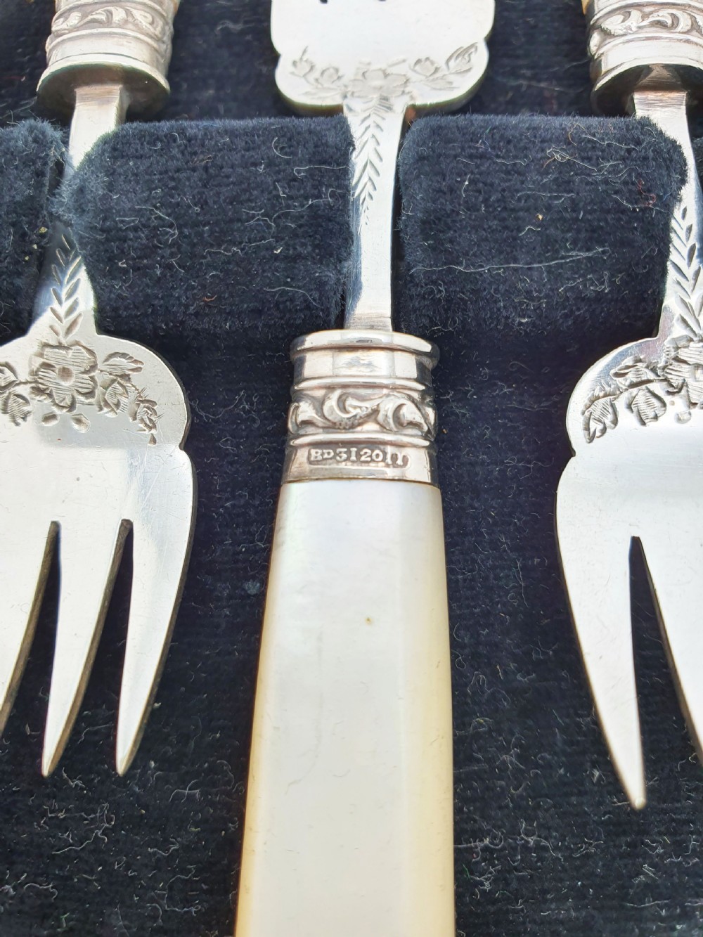 A cased set of six Victorian hors doeuvres forks featuring mother-of-pearl handles and engraved silver-plated tines, presented in a blue fabric-lined box. View V