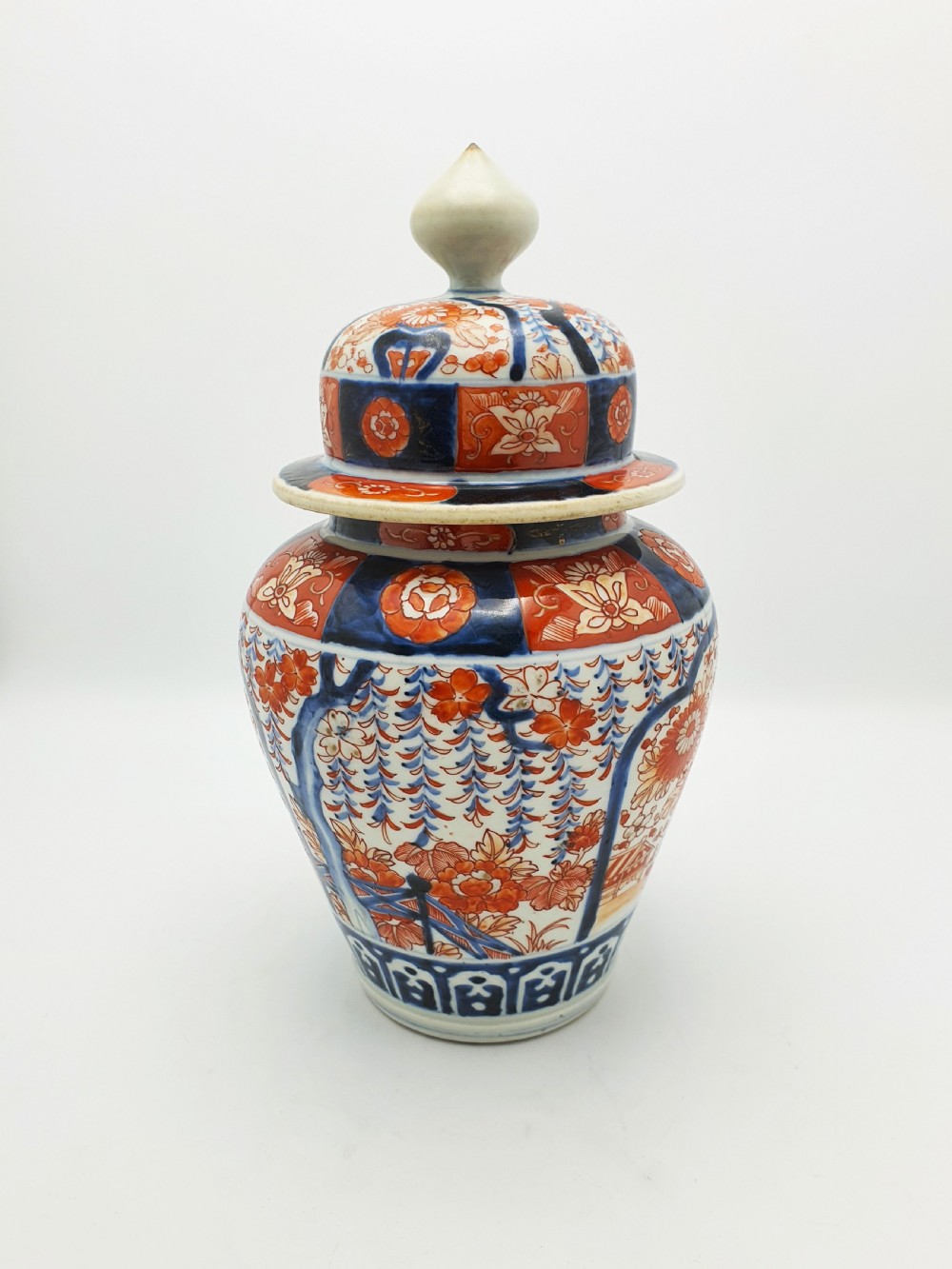 A Japanese Imari porcelain covered ginger jar decorated with hand-painted iron-red and cobalt-blue floral panels, complete with a domed lid and pointed finial. View III