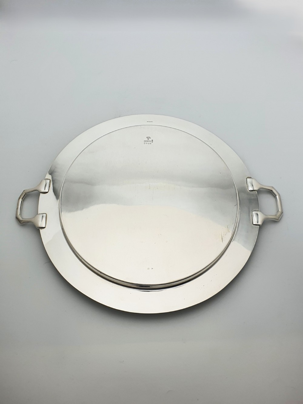 A circular Art Deco silver-plated serving tray featuring angular geometric handles and a simple raised border. View III
