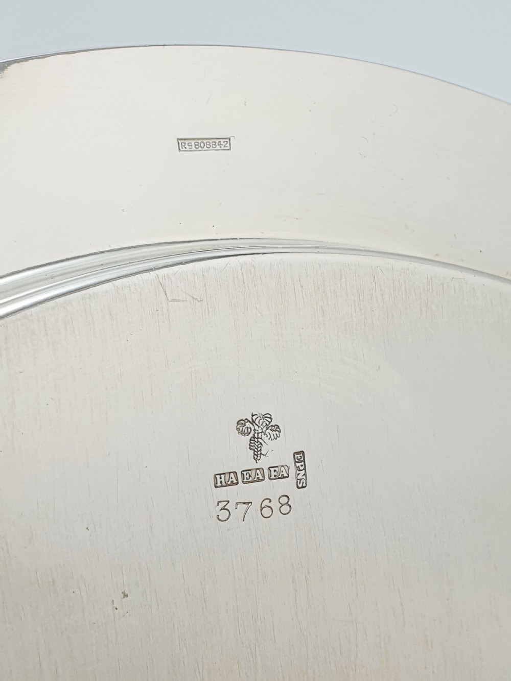 A circular Art Deco silver-plated serving tray featuring angular geometric handles and a simple raised border. View IV