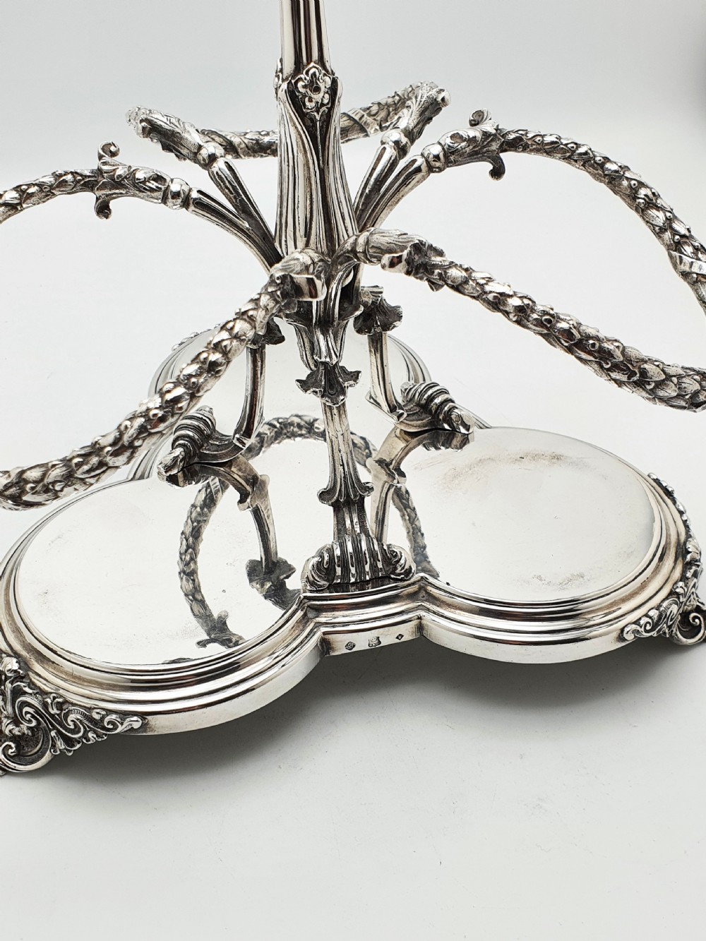 A Victorian silver-plated three-bottle decanter stand holding three clear cut-glass decanters with matching stoppers. View VI