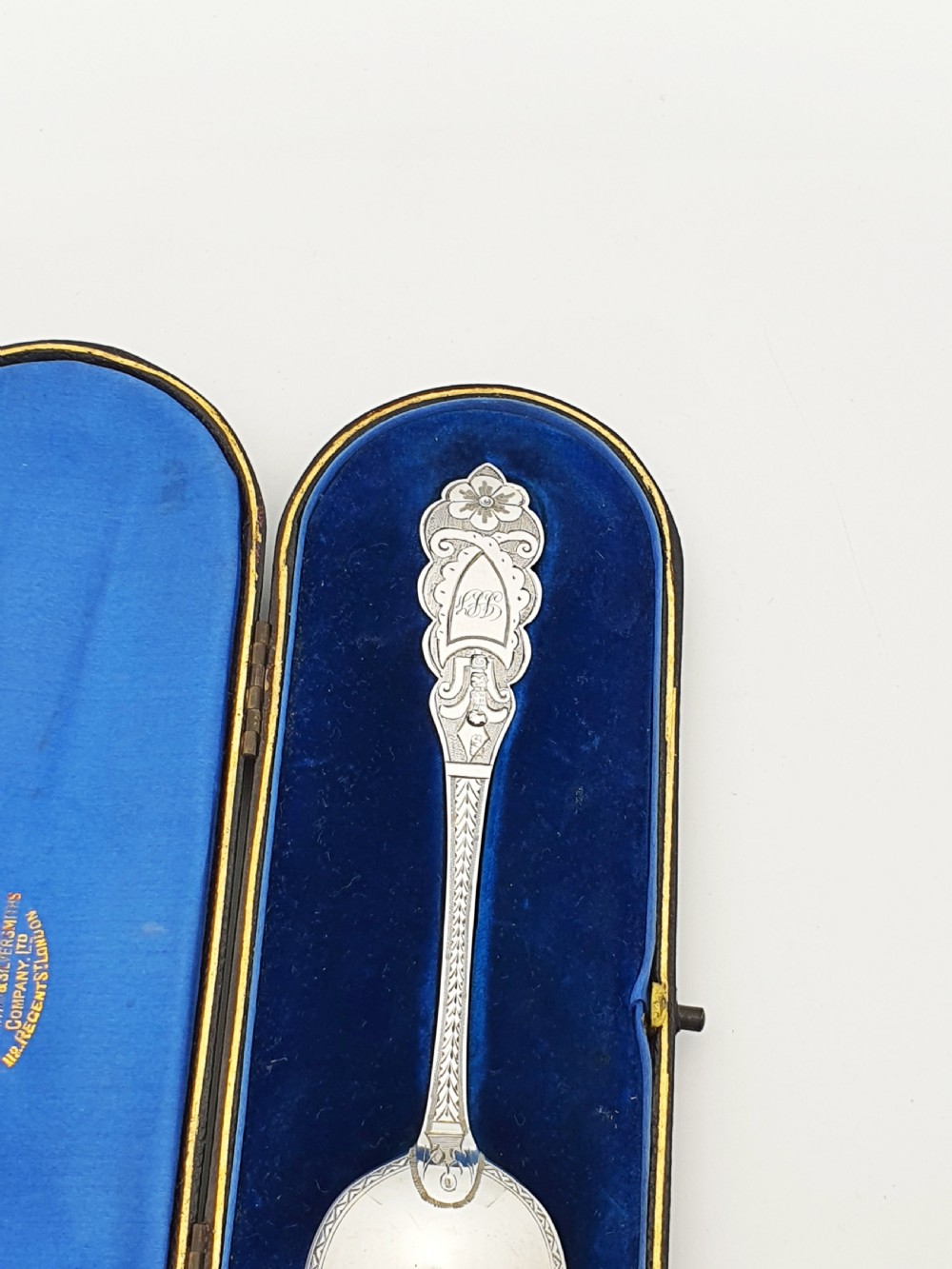 An 1877 Victorian sterling silver presentation spoon with an engraved stag motif inside an open blue velvet presentation box. View III