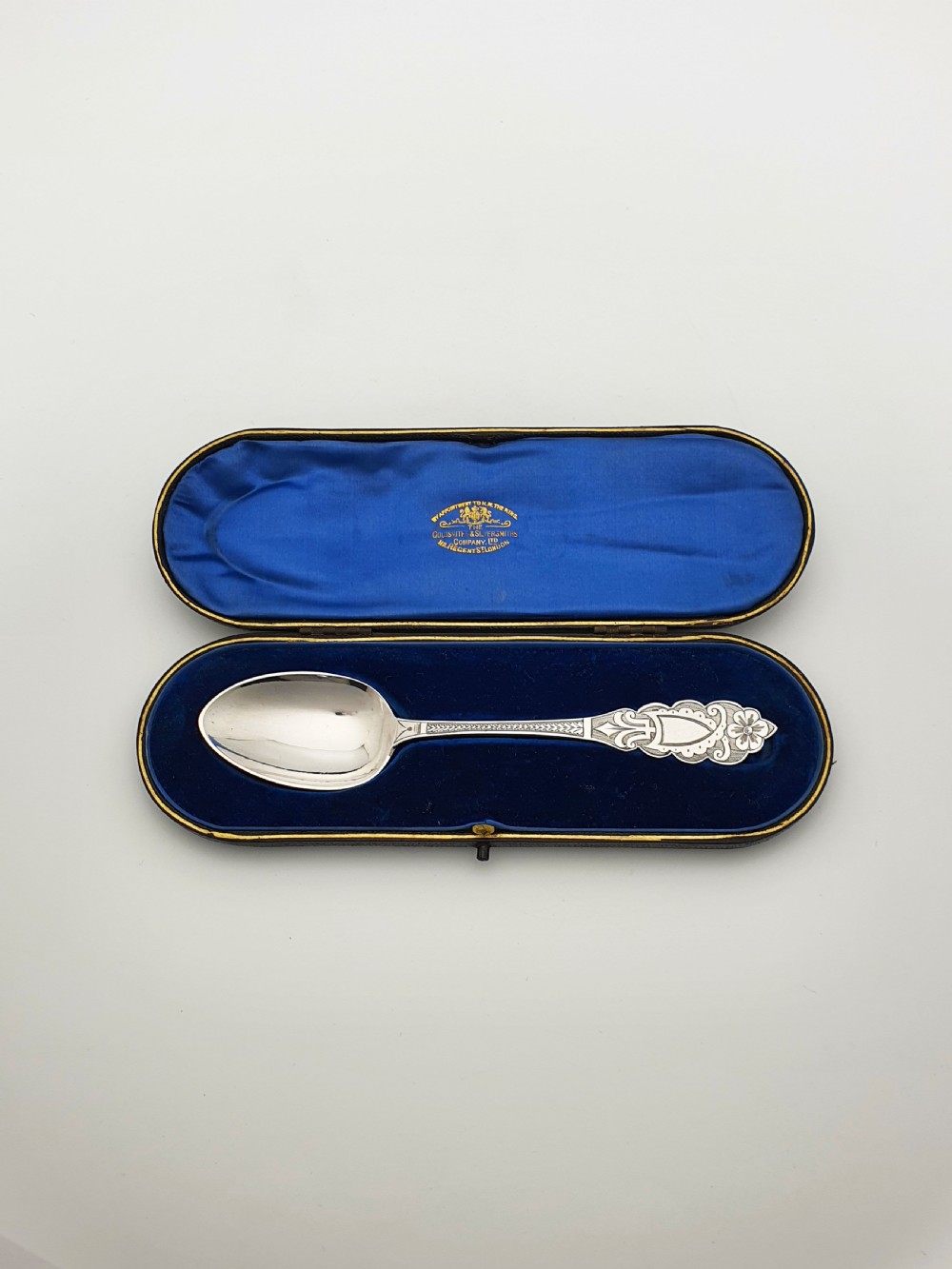 An 1877 Victorian sterling silver presentation spoon with an engraved stag motif inside an open blue velvet presentation box. View V