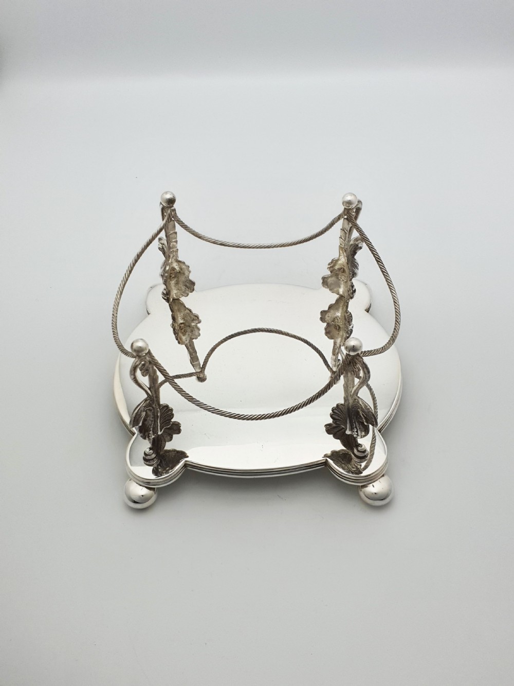 An oval cut crystal biscuit barrel featuring silver-plated mounts, ball feet, twisted rope swags, and an engraved lid topped with a heraldic dragon finial. View XI
