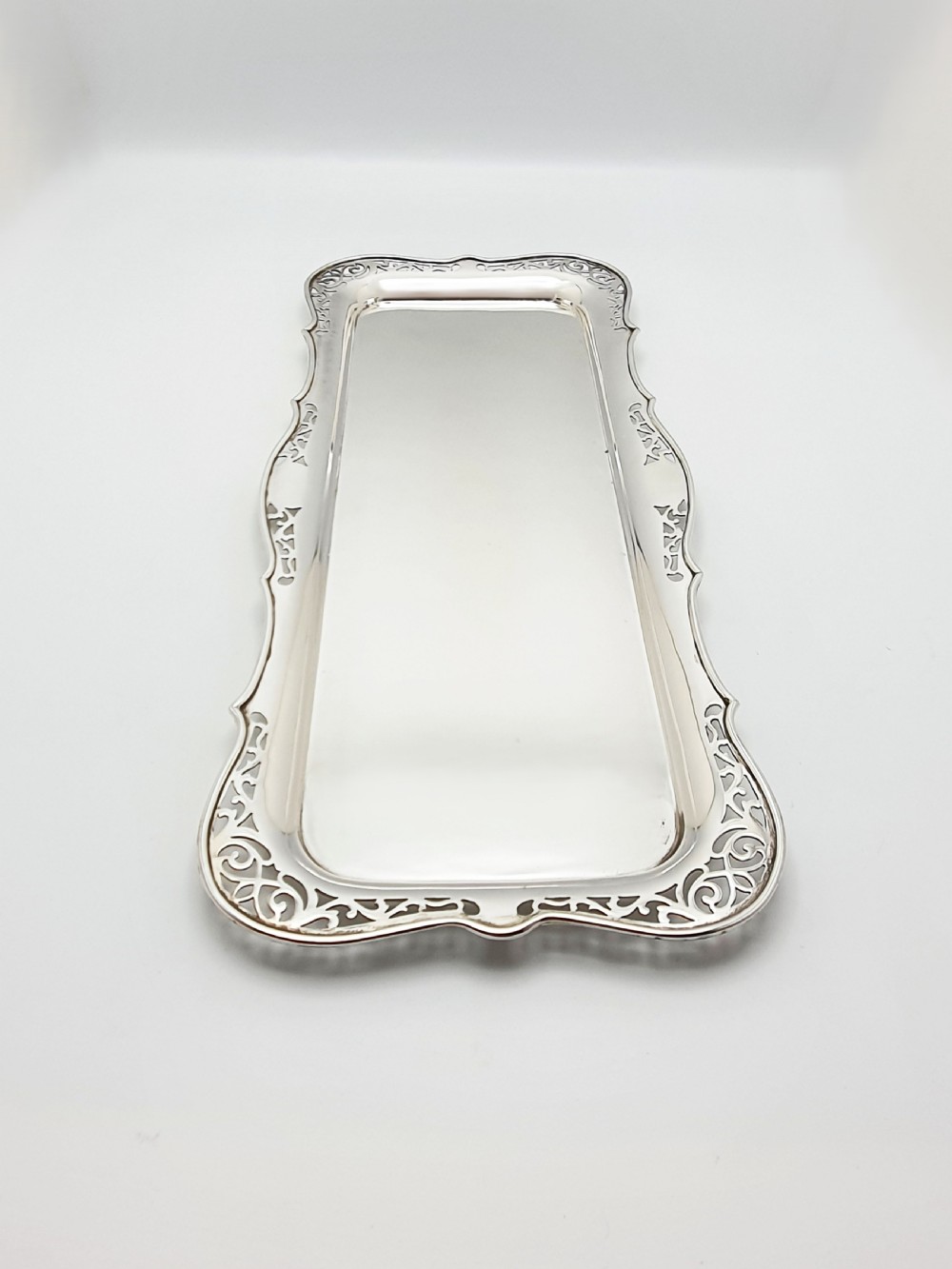 A rectangular silver-plated cocktail tray featuring a pierced scrollwork border and a smooth reflective centre. View III