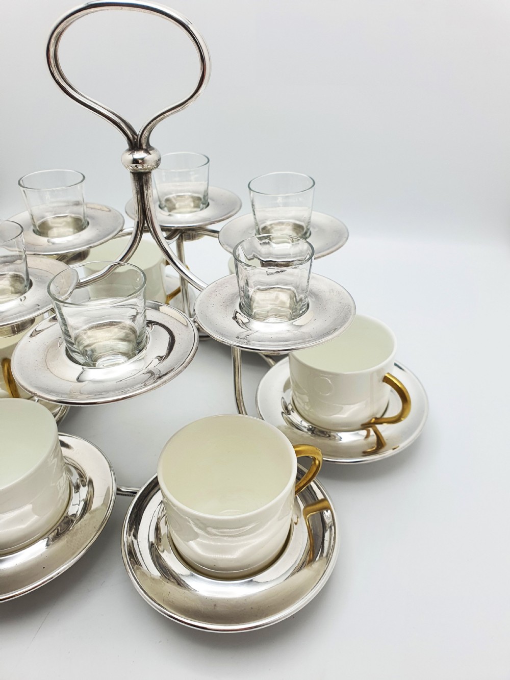 A silver-plated tiered service stand holding six cream ceramic demitasse cups on the lower level and six glass liqueur cups above. View II