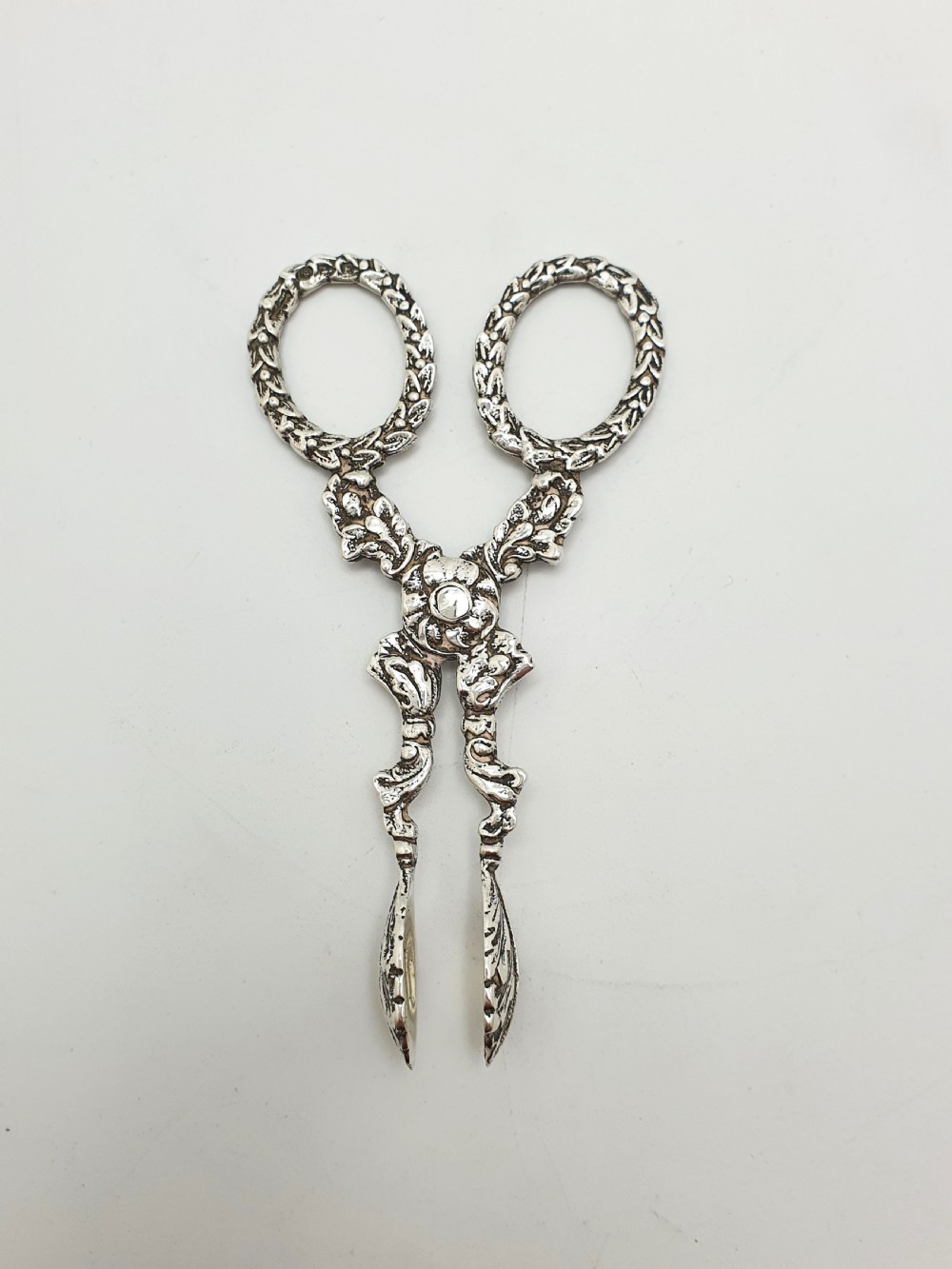 A pair of late Victorian sterling silver scissor-action sugar nips featuring floral relief motifs, round finger loops, and spoon-shaped tips. View III