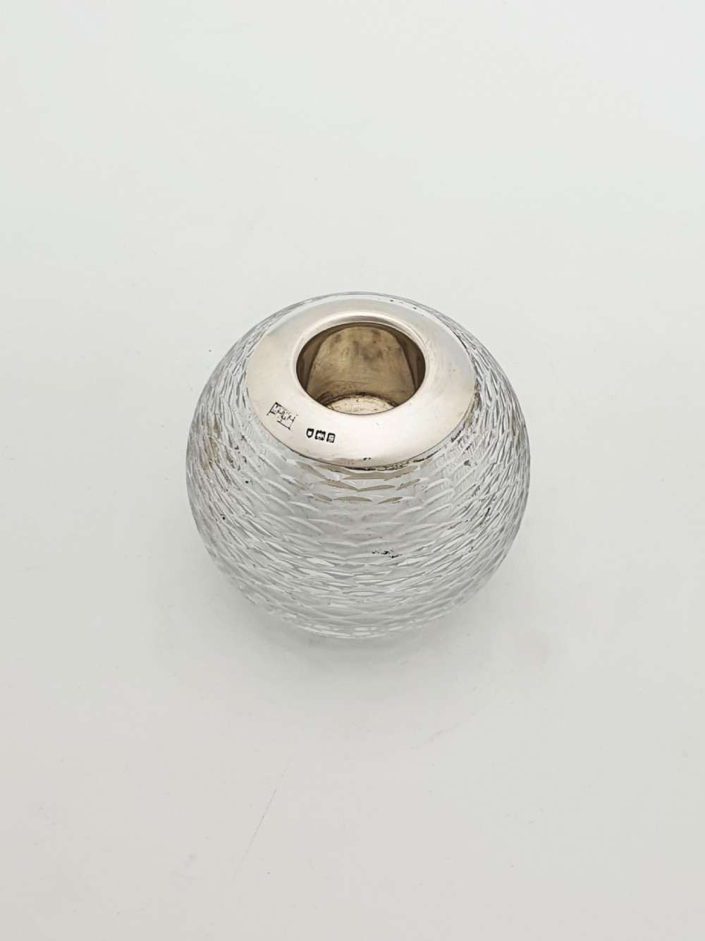 An Edwardian spherical glass match striker featuring a textured rib outer surface and a hallmarked sterling silver collar at the top aperture.