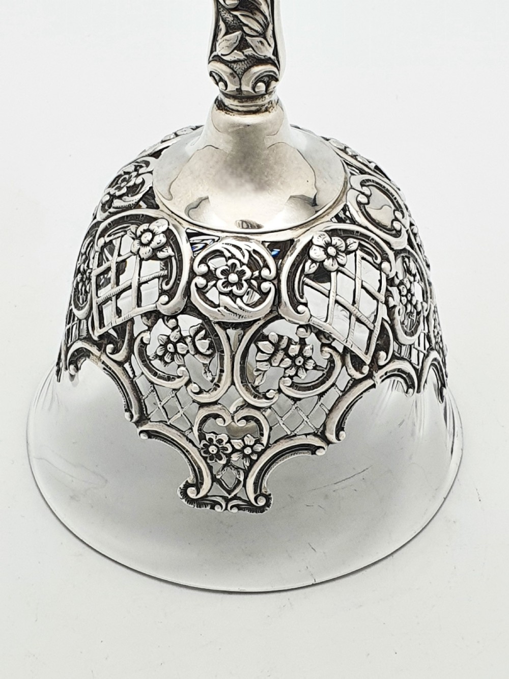 A late Victorian sterling silver and clear glass table bell with a figural handle and ornate pierced silver overlay. View III