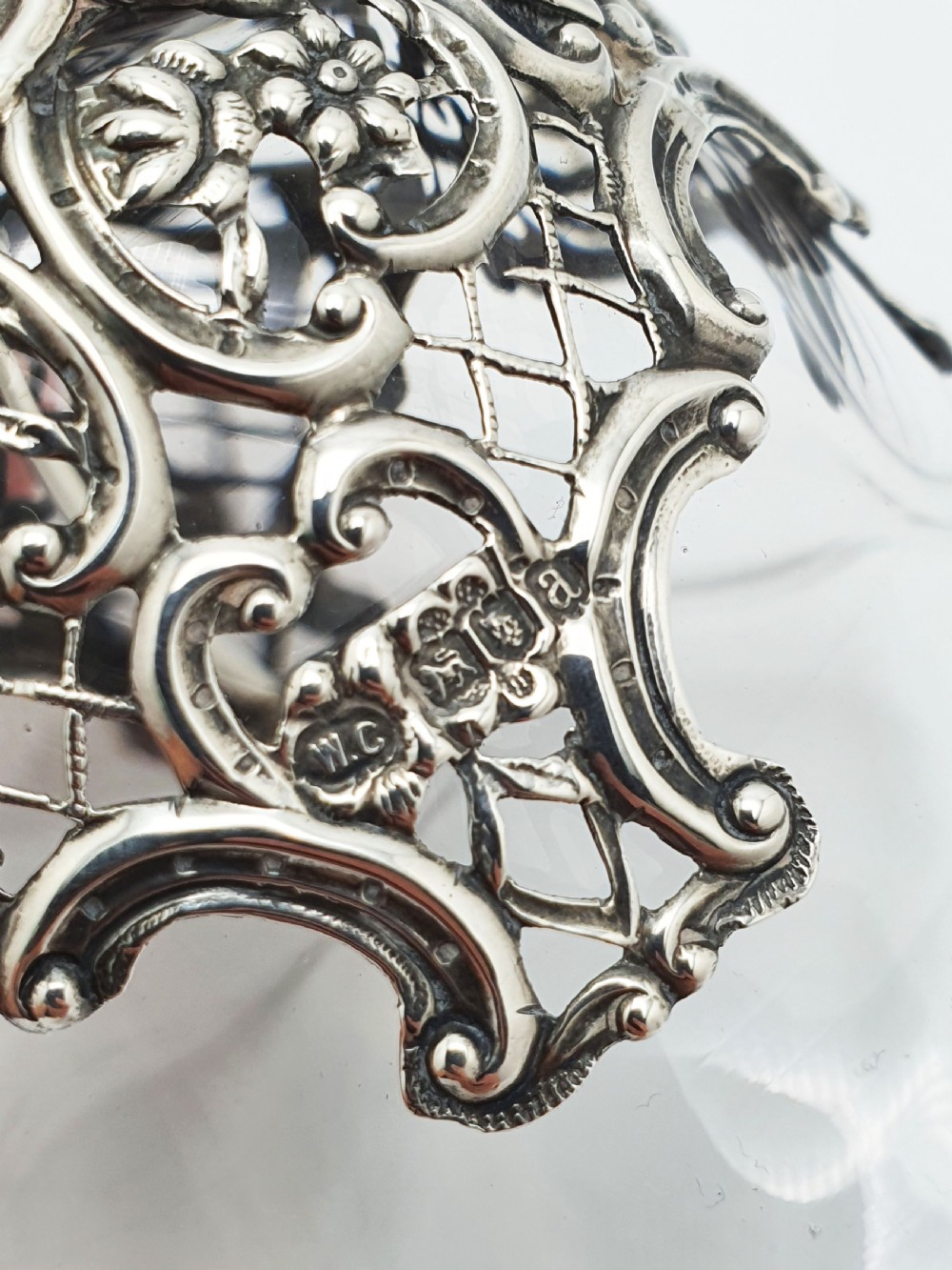 A late Victorian sterling silver and clear glass table bell with a figural handle and ornate pierced silver overlay. View VI