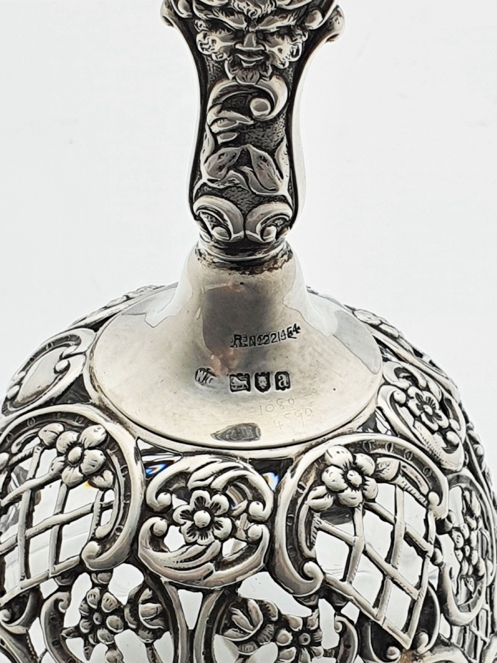A late Victorian sterling silver and clear glass table bell with a figural handle and ornate pierced silver overlay. View VII