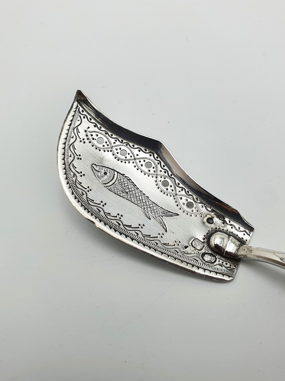 An antique silver sardine server featuring an engraved fish motif on a curved blade and a slender turned dark wooden handle. View III