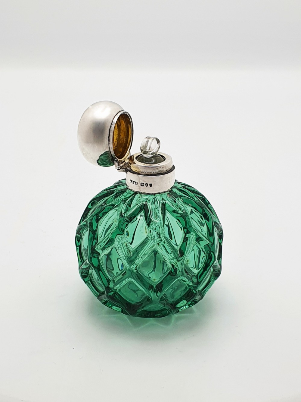 An antique round emerald green cut glass perfume bottle with a sterling silver domed top. View V