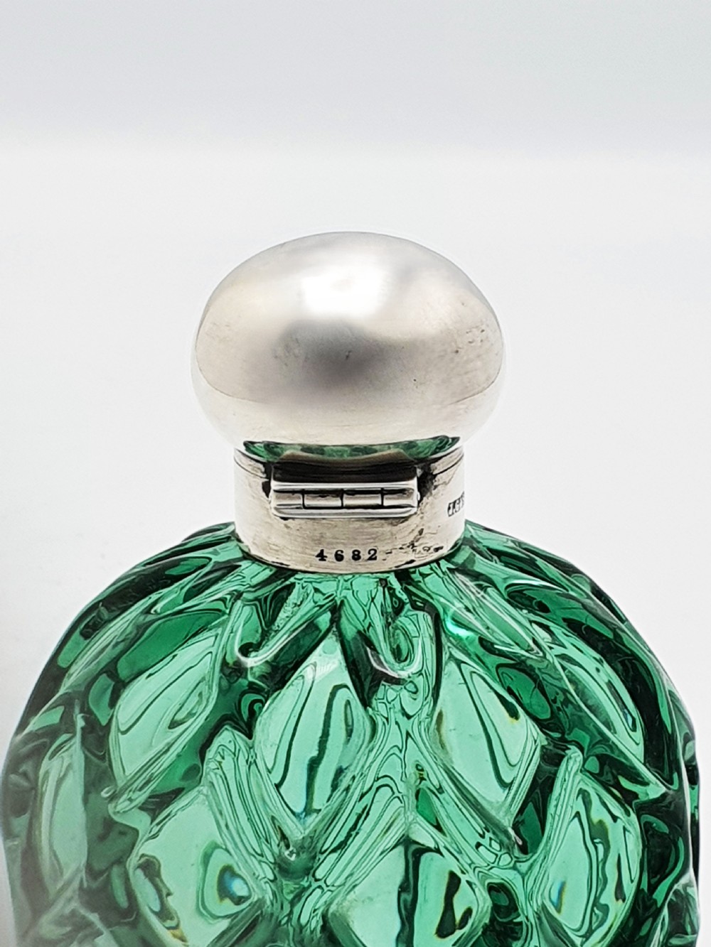 An antique round emerald green cut glass perfume bottle with a sterling silver domed top. View VI