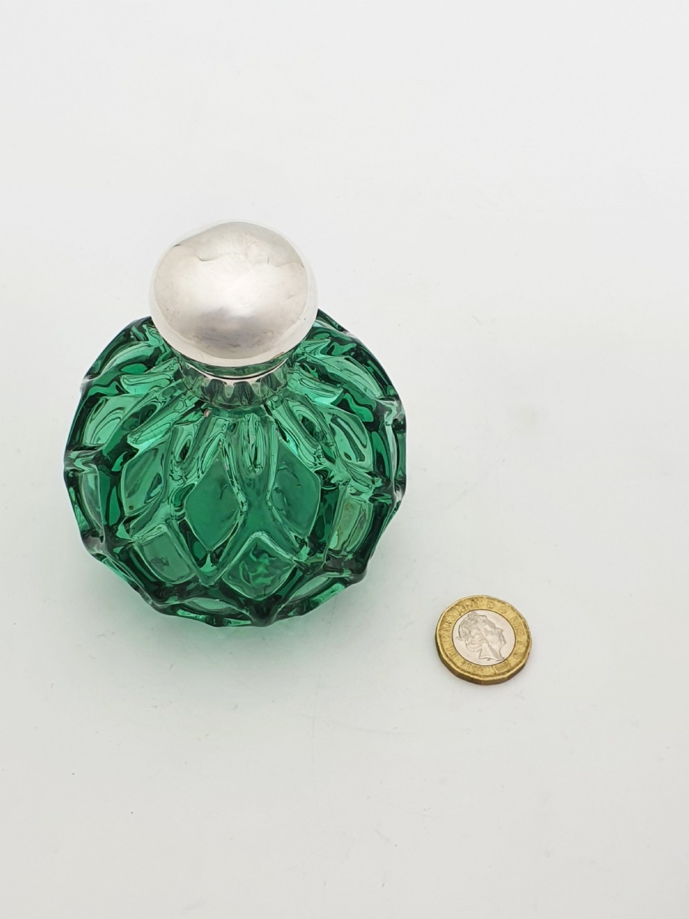 An antique round emerald green cut glass perfume bottle with a sterling silver domed top. View VIII