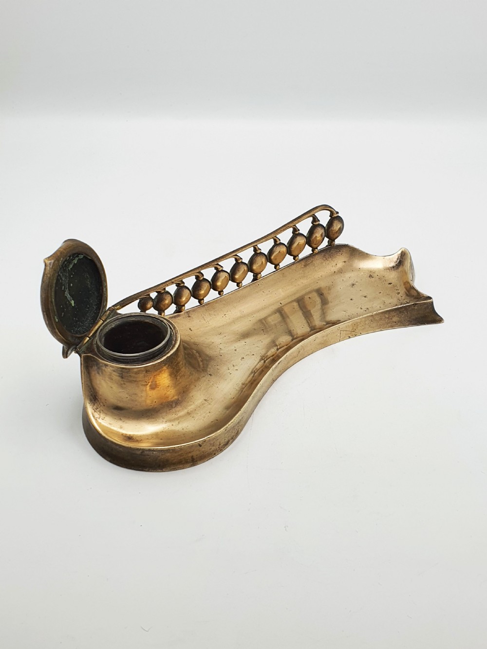 An Art Nouveau cast bronze inkwell featuring a hinged lid, organic curved pen rest tray, and decorative beaded back gallery. View II