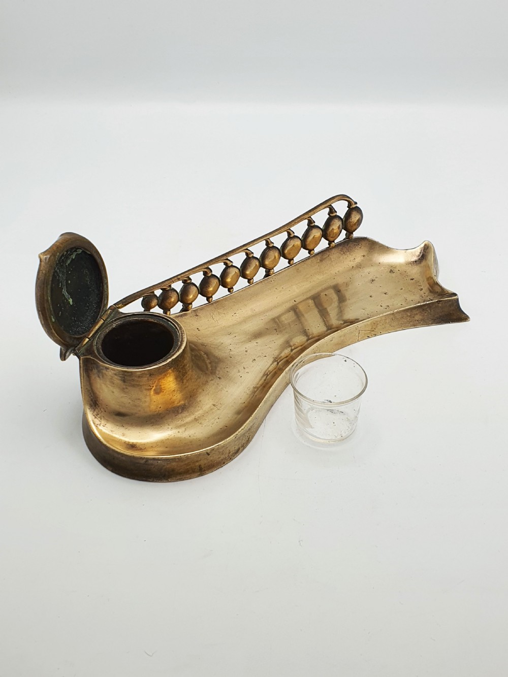 An Art Nouveau cast bronze inkwell featuring a hinged lid, organic curved pen rest tray, and decorative beaded back gallery. View III