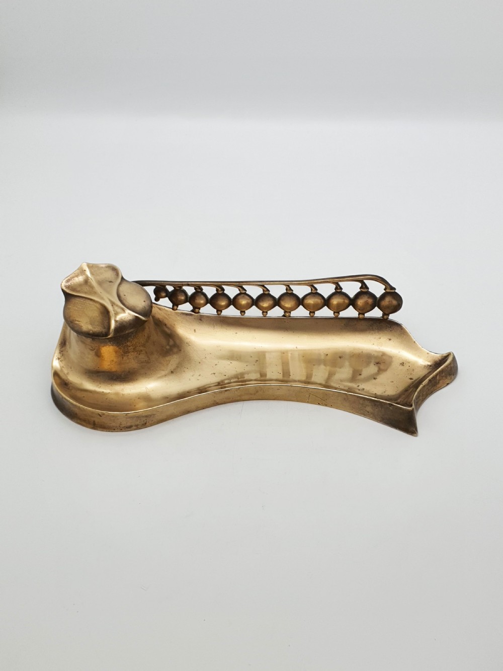 An Art Nouveau cast bronze inkwell featuring a hinged lid, organic curved pen rest tray, and decorative beaded back gallery. View V