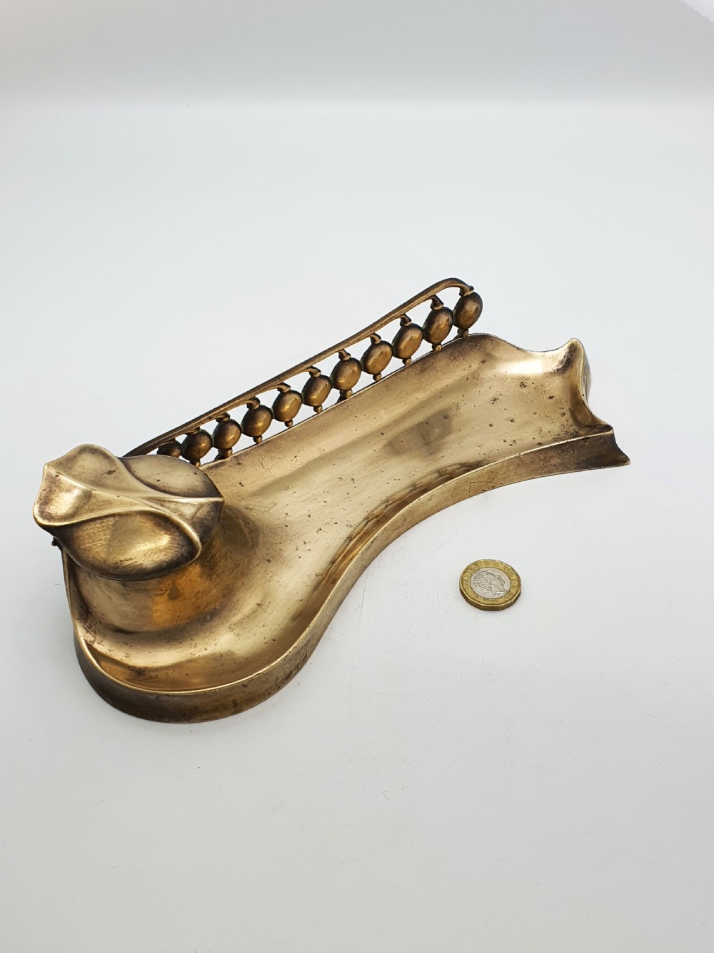 An Art Nouveau cast bronze inkwell featuring a hinged lid, organic curved pen rest tray, and decorative beaded back gallery. View IX