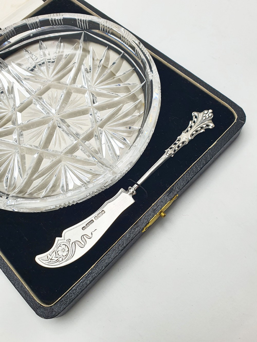 A circular cut crystal butter dish and a hallmarked sterling silver spreader presented inside a fitted black box. View V